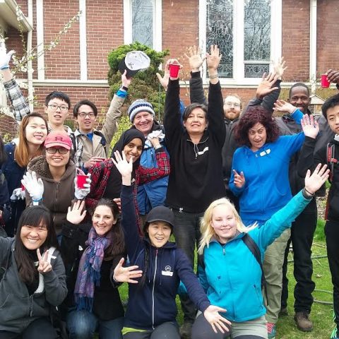 A group photo of 16 Transition Toronto volunteers with their hands in the air